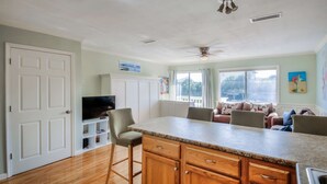 Una cocina con una isla central, armarios de madera, televisor integrado y ventilador de techo.