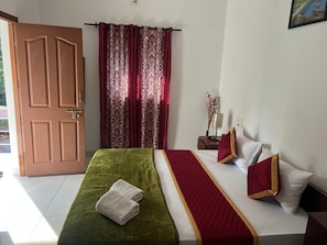 Une chambre d’hôtel avec un lit, une table de chevet, une lampe et une porte.
