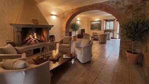 A cozy living room with a fireplace, comfortable seating, and a stone archway. - Borgo di Erboli (Cavriglia)