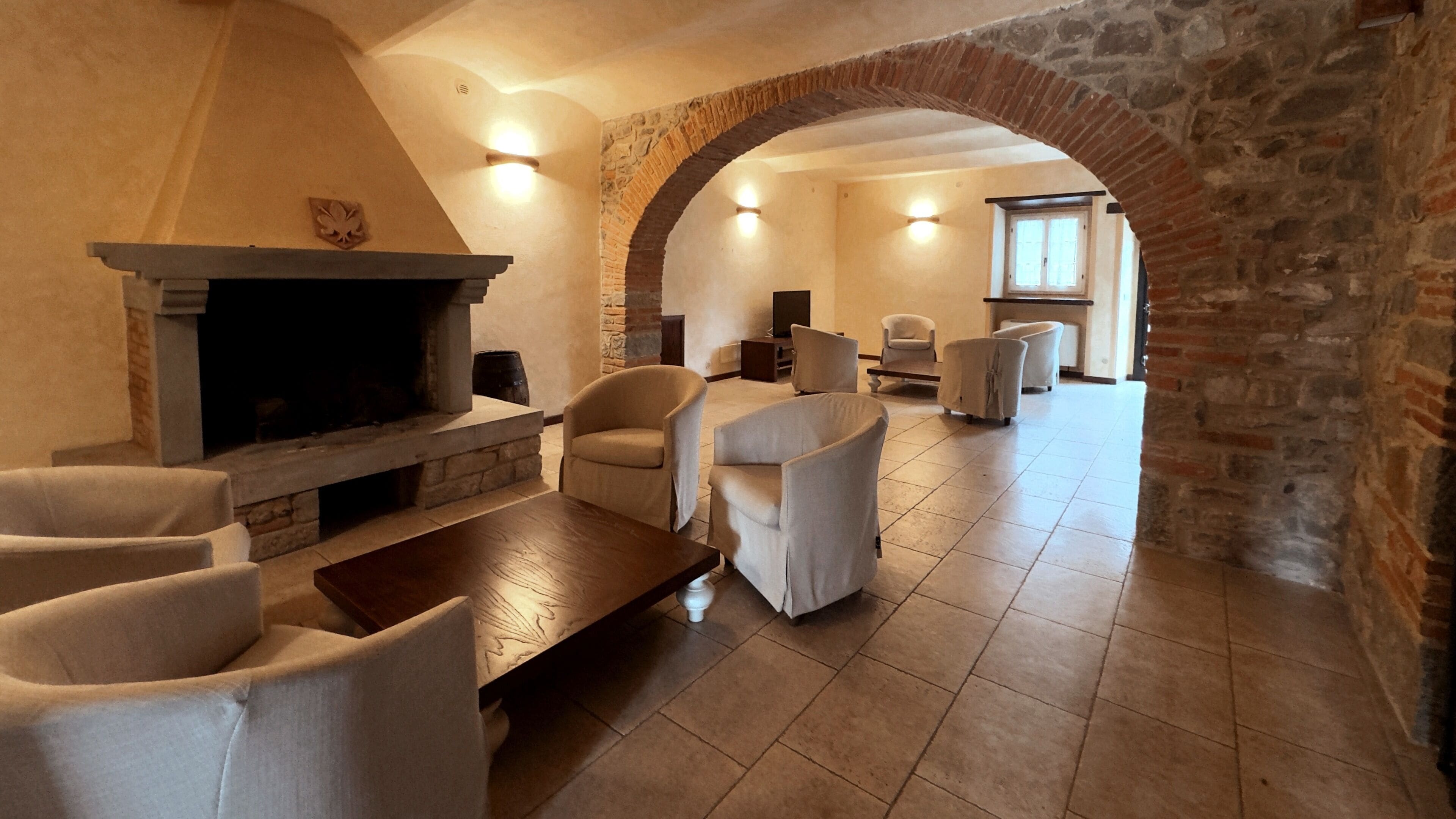 Una sala de estar acogedora con chimenea, asientos confortables y un arco de piedra.
