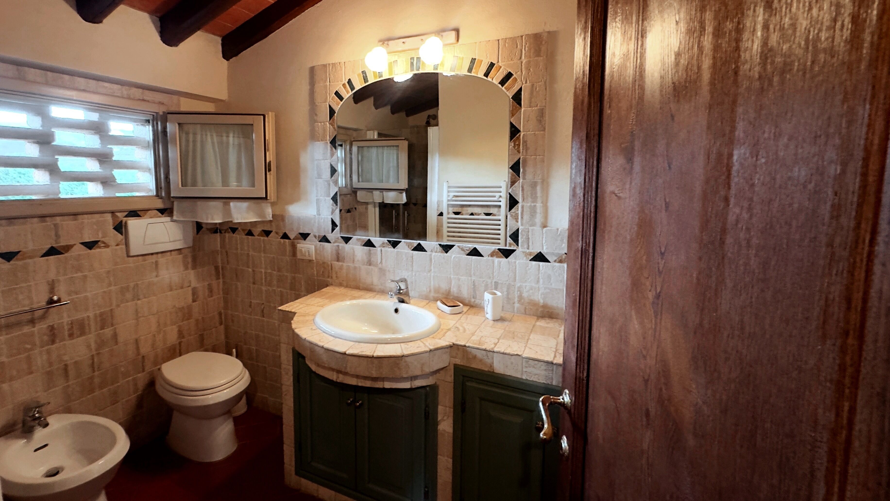 Ein Badezimmer mit Toilette, Bidet, Waschbecken und Spiegel.