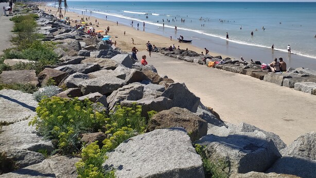 Una playa rocosa con vistas claras del océano y una orilla arenosa.