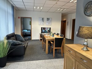 A modern office space with a conference table, chairs, a sofa, and a lamp. - Bordinghouse Halverde (Hopsten)