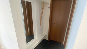 Un couloir avec une fenêtre, une porte et un objet en bois fixé au mur.