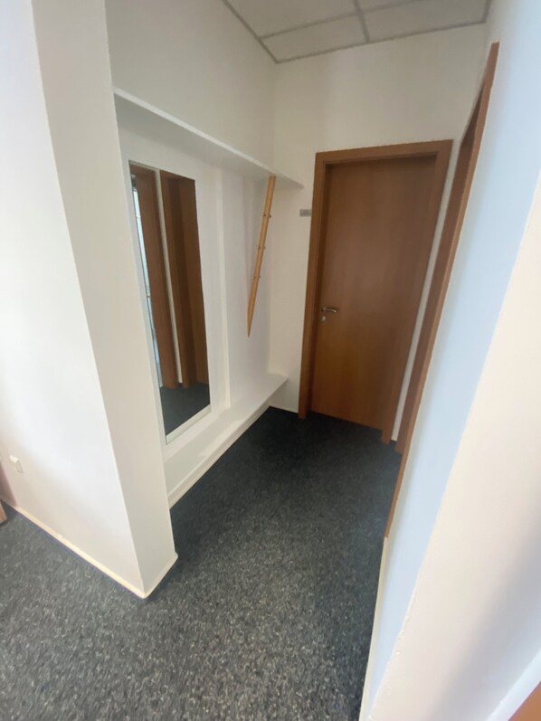 A hallway with a window, a door, and a wall-mounted wooden object. - Bordinghouse Halverde (Hopsten)