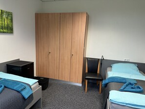 A room with two beds, a wooden wardrobe, a chair, and a small table. - Bordinghouse Halverde (Hopsten)