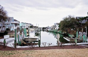 A marina with boats docked, a calm waterway, and residential buildings on both sides. - Central OBX Getaway with Pool and Sound Access (Nags Head)