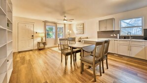 Une cuisine moderne avec un plancher en bois, un coin repas avec une table et des chaises, et un ventilateur de plafond.