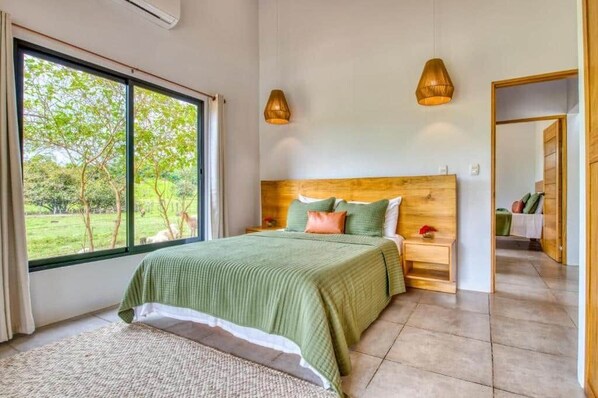 A bedroom with a large window, a wooden headboard, and two bedside lamps.