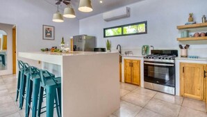 Una cucina moderna con un'isola centrale, sgabelli da bar, un fornello e un frigorifero.