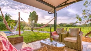 Un'area relax all'aperto riparata, con mobili in vimini, un'amaca e vista su un paesaggio rigoglioso.