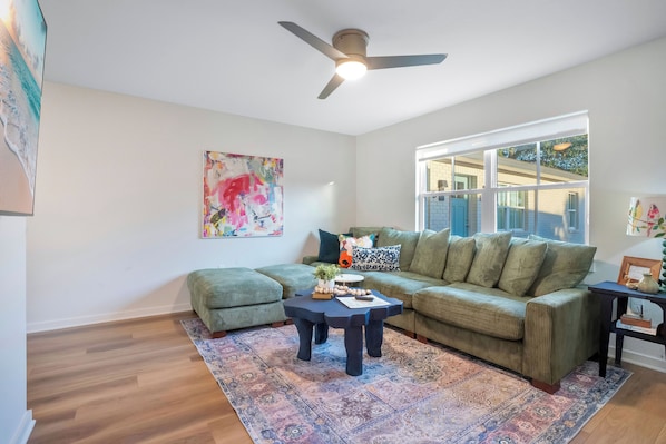 A living room with a green sofa, a dark coffee table, and a patterned rug. - Modern Comfort Belmar Lofts Apartment C Lk Hollingsworth 2 King Suites (Lakeland)