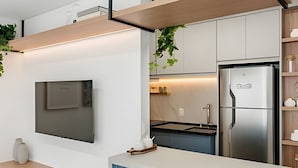 Une cuisine moderne dotée d’un réfrigérateur encastré, d’un téléviseur fixé au mur et d’un plan de travail en bois.