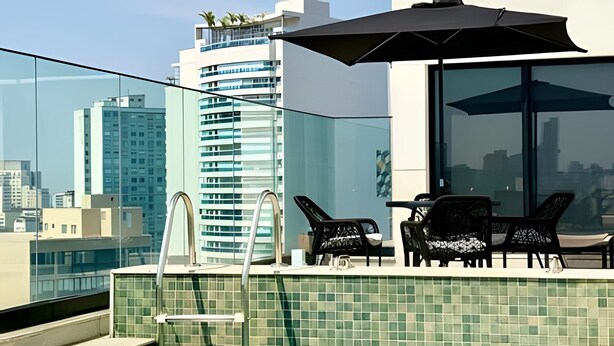 Une terrasse sur le toit avec une piscine, des chaises longues et une vue sur le panorama urbain.