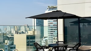 Un balcon doté d’une balustrade en verre, une table avec des chaises et un grand parasol.
