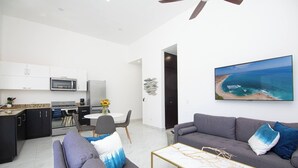 Un salon moderne avec un canapé gris, une table basse et un téléviseur fixé au mur.