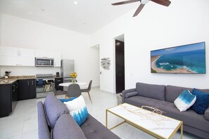 Una sala de estar moderna con un sofá gris, una mesa de centro y un televisor montado en la pared.