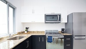 Une cuisine moderne dotée d’un comptoir en granit, d’appareils électroménagers en acier inoxydable et de meubles de cuisine noirs.