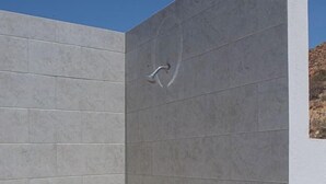 Un espace douche moderne avec des carreaux gris et une pomme de douche visible.