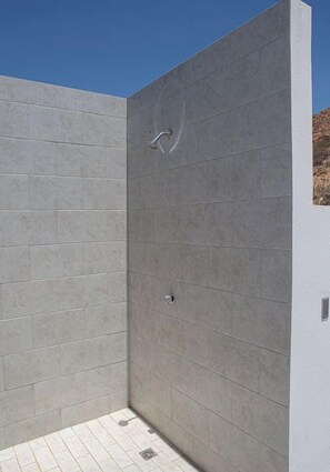 Un espacio de ducha moderno con azulejos grises y un cabezal de ducha visible.