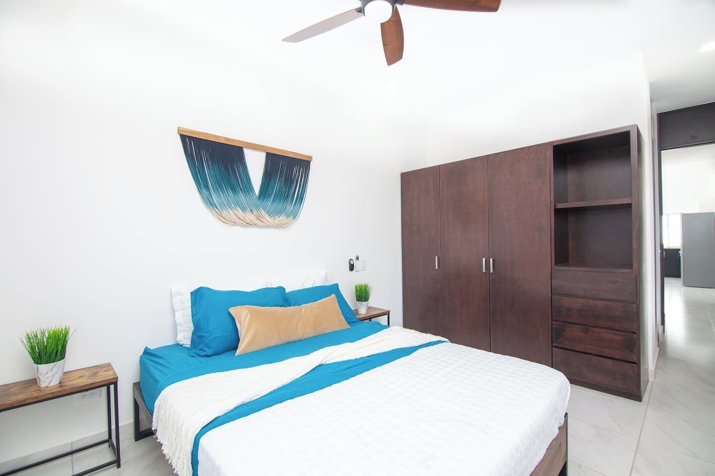 Een slaapkamer met een bed, een kledingkast, een plafondventilator en een kunstwerk aan de muur.