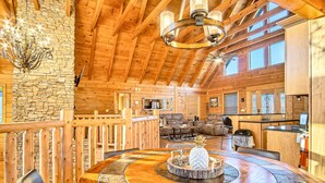A spacious wooden interior with a round dining table, stone accents, and a stone wall. - Luxe Sister Cabins, Sleeps 24, Pool, Hot Tub, Games (Gatlinburg)