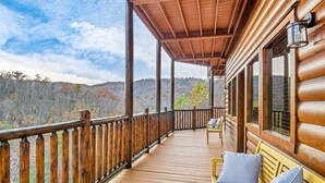 A wooden deck with a railing, benches, and a view of a forested mountain range. - Luxe Sister Cabins, Sleeps 24, Pool, Hot Tub, Games (Gatlinburg)