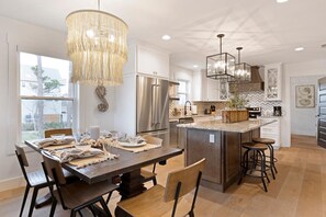 A modern kitchen with a central island, stainless steel appliances, and a chandelier. - Delimara at the Cape (Port St. Joe)