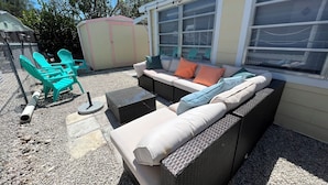 A patio area with outdoor furniture, including a sofa and chairs, and a covered play area.