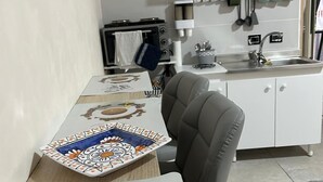 Cocina compacta con microondas, tostadora y lavabo. Hay tazas de café y un plato con granos de café sobre la mesa.