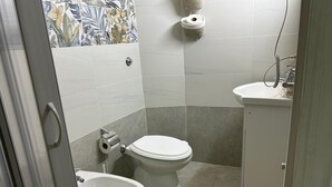 Un baño pequeño con inodoro, bidé y lavamanos.