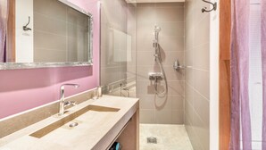 Een badkamer met een wastafel, spiegel, douche en betegelde wanden.
