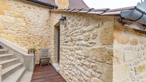 A stone building with a staircase leading to a door, a metal railing, and a potted plant. - Tilleul Room – Natural Comfort and Spaciousness (Carsac-Aillac)