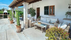 Eine Terrasse im Freien mit einer Couch, einem Tisch und Blumentöpfen.