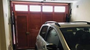 A vehicle parked inside a building with a tiled floor and a wooden door. - Fenced apartment (additional garage) (San Salvador)