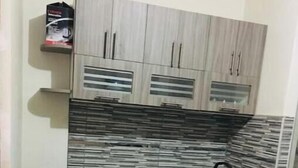 A compact kitchen with a gas stove, a small round table, and a chair. - Fenced apartment (additional garage) (San Salvador)