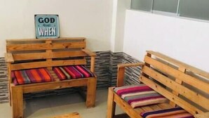 Two wooden benches with colorful cushions, a small wooden table, and a sign on the wall. - Fenced apartment (additional garage) (San Salvador)