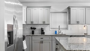 A modern kitchen with grey cabinets, a stainless steel refrigerator, a granite countertop, and a built-in oven. - 3BR Apt Mins to Bus, Newark Airport, Penn Sta, NYC (Newark)
