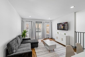 A modern living room with a grey sectional sofa, a white coffee table, and a TV mounted on the wall. - 3BR Apt Mins to Bus, Newark Airport, Penn Sta, NYC (Newark)