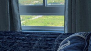 Uma cama com vista para uma paisagem pela janela.
