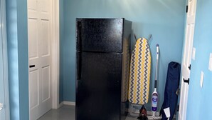 Cozinha compacta com geladeira preta, porta branca e parede azul.