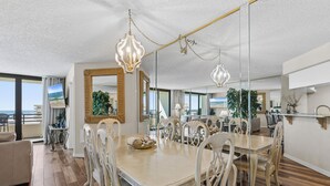 Une salle à manger spacieuse, dotée d’une grande table, d’élégantes chaises et de lustres suspendus.