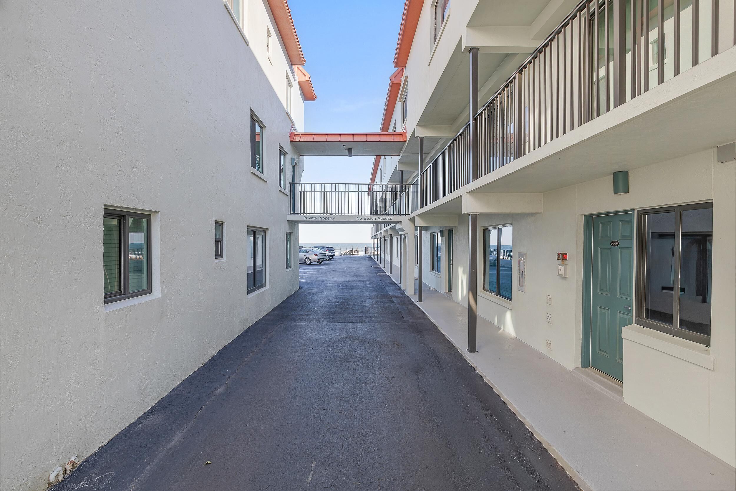 A narrow corridor with a clear sky above, leading to a gated entrance.
