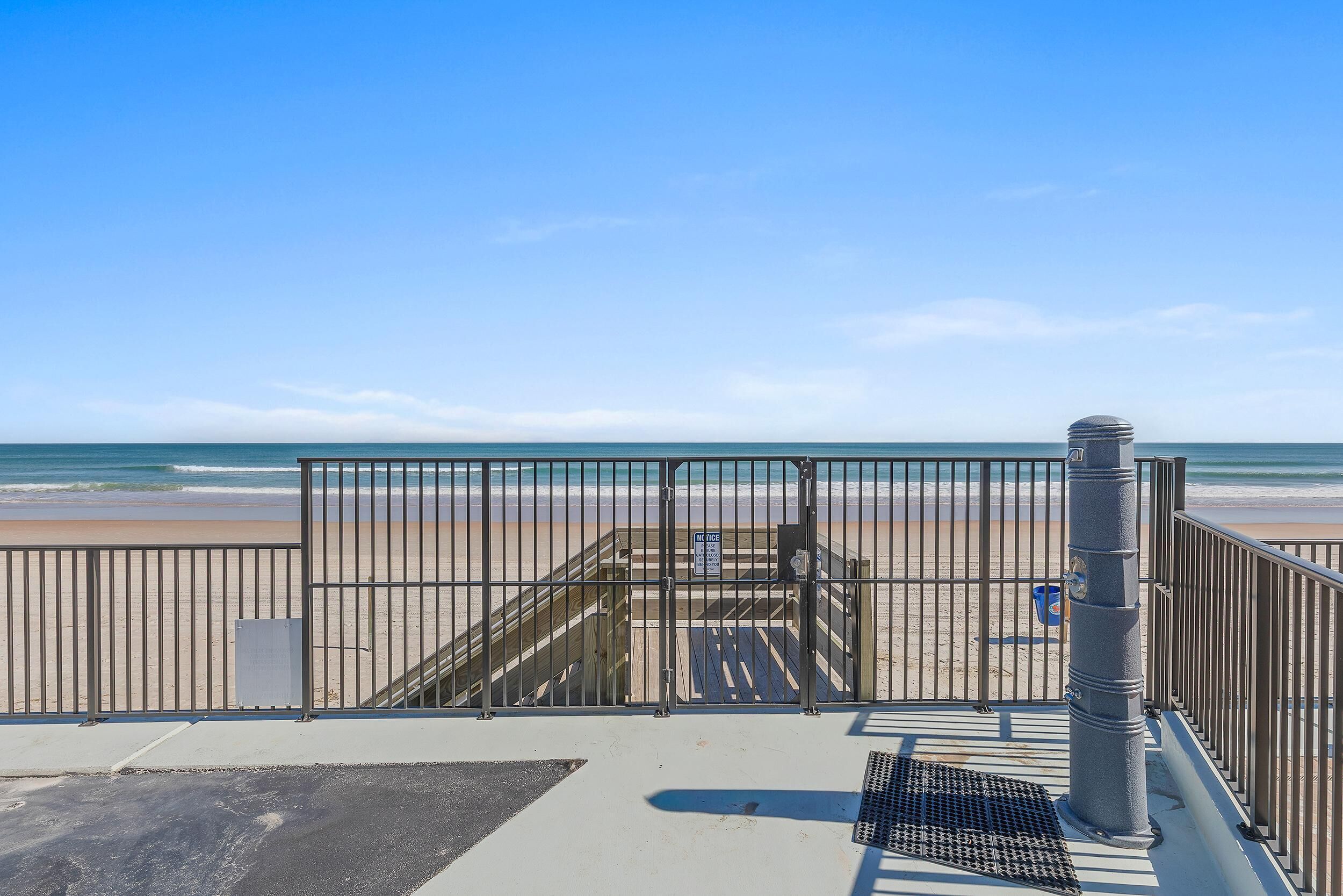 A beach view with a metal railing and a staircase leading to a beach access point.