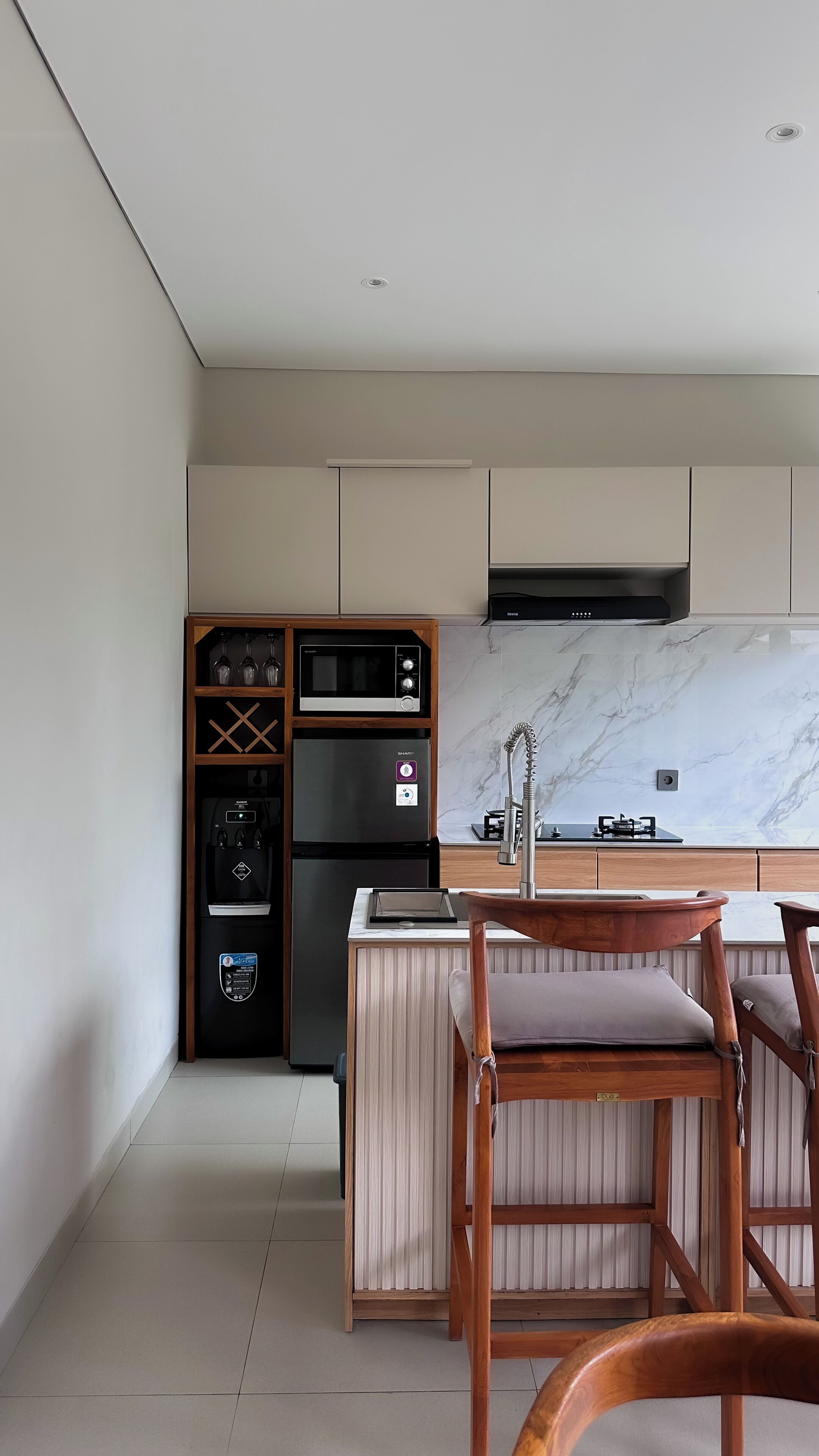 A modern kitchen with a built-in microwave, oven, and refrigerator, a wooden dining table with chairs, and a marble backsplash.