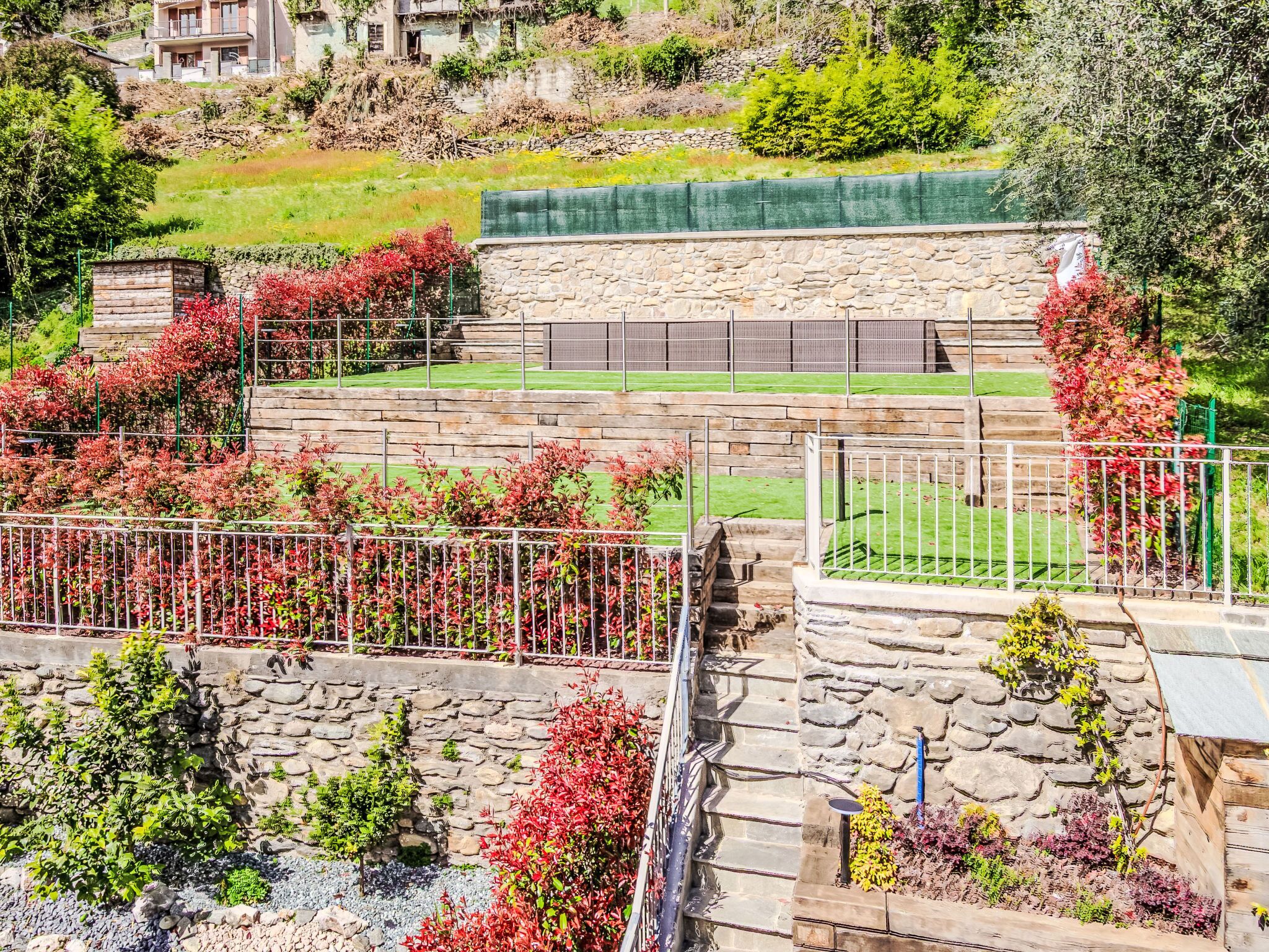 A stone staircase leading to a terrace with a view of a hillside and a building in the background.