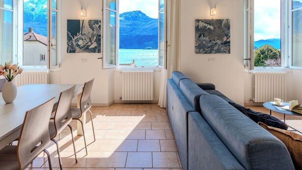 Una habitación moderna con sofá, mesa de comedor, sillas y ventanas amplias con vistas a las montañas.