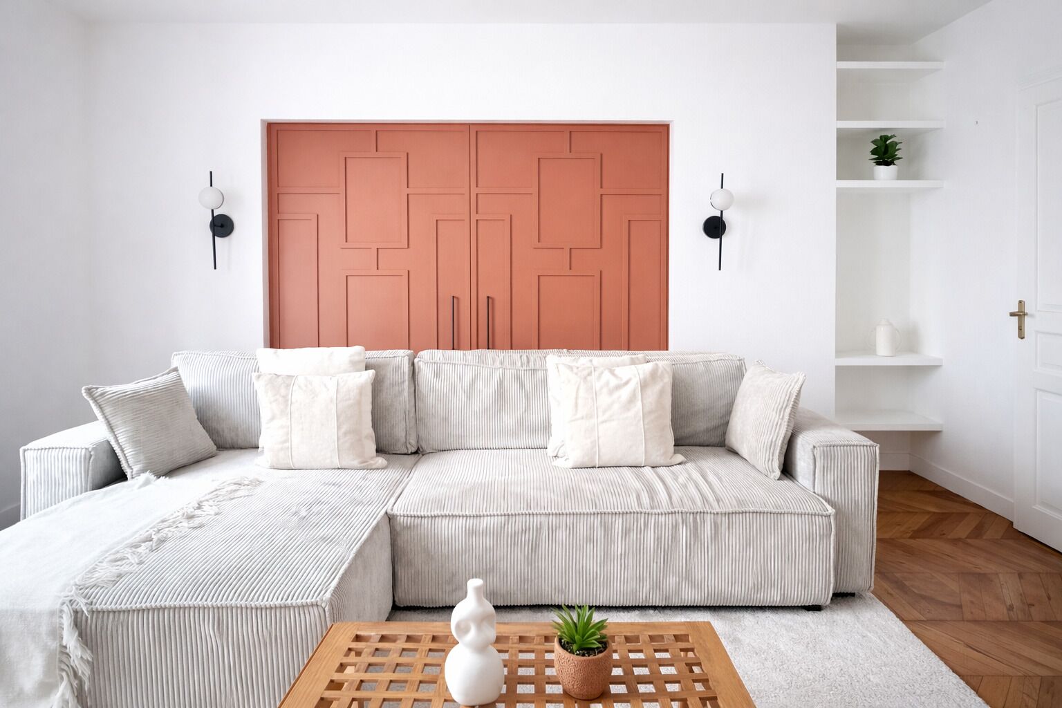 A modern living room with a sectional sofa, a coffee table with decorative items, and a large geometric-patterned door.
