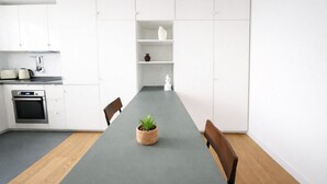 Une cuisine moderne avec des armoires blanches, un four encastré et un plan de travail gris.