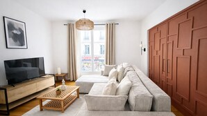Un salon moderne avec un canapé, un téléviseur et une table basse en bois.